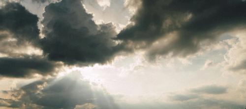 A sky with dark storm clouds and rays of sun shining through.