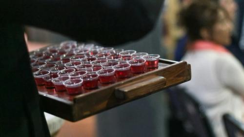 Communion tray of wine held by a man in church.