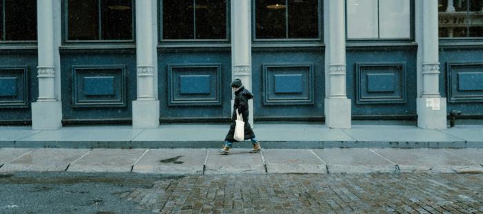 A woman in a raincoat walking down a sidewalk
