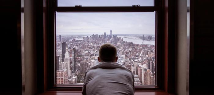 man in gray shirt looking at city buildings during daytime
