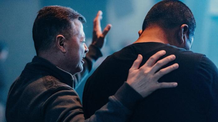 Pastor and man praying and worshipping at church together.