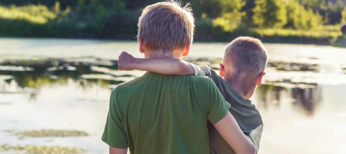 two brothers standing in front of a pond together