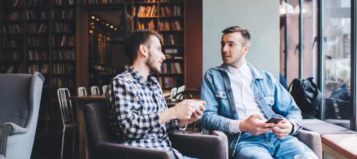 two men in a coffee shop sharing and talking