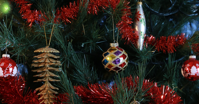 ornaments and pinecone hanging from tree with red tinsel