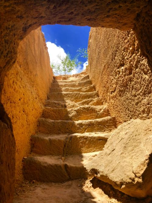 CC- A blue sky is visible from the bottom of a set of stone stairs coming out of an ancient basement.