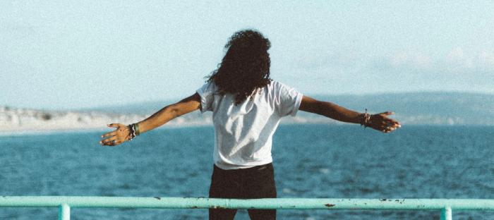 person standing on edge of the pier with arms open