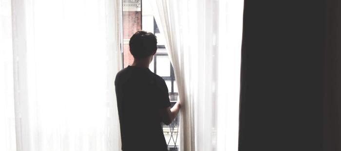 a man standing in front of a window looking out