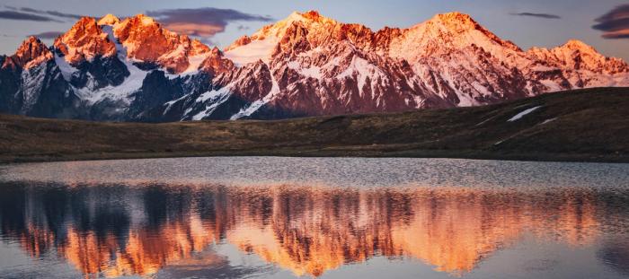 snowy mountains in the sunset, reflecting on the water