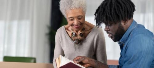 Older woman reading Bible with young man
