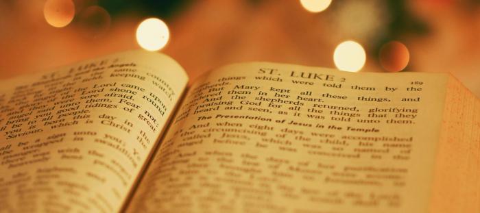 The Bible opened to the book of Luke in front of twinkly lights