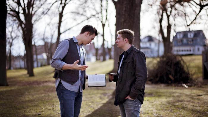 Two men speaking to one another with a Bible in hand.