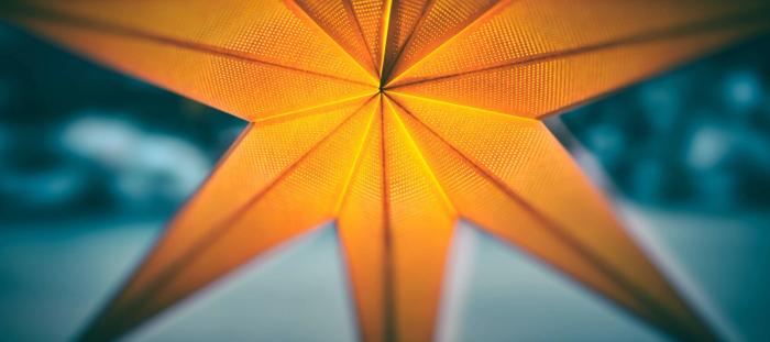 CC-  shallow-focus photo of a lighted orange seven-pointed star against a blurred blue background