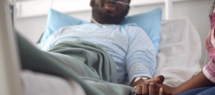 Cropped shot of african wife visiting husband in hospital holding hands and supporting