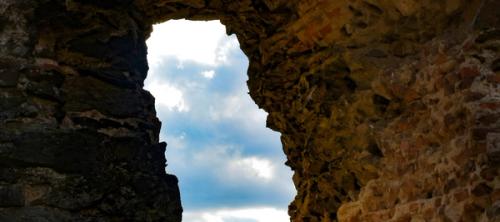 A cloudy sky visible through a crevice in a rocky cliff.