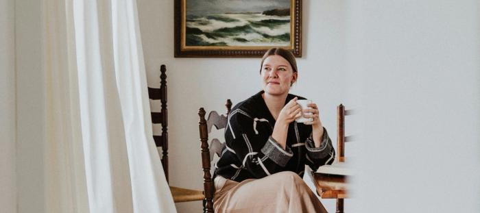 A woman contentedly sitting in a chair and holding a mug