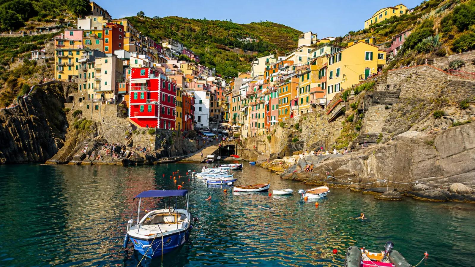 Scorcio panoramico del porticciolo di Riomaggiore, con le tipiche case-torri colorate affacciate sul mare e le barche ormeggiate.