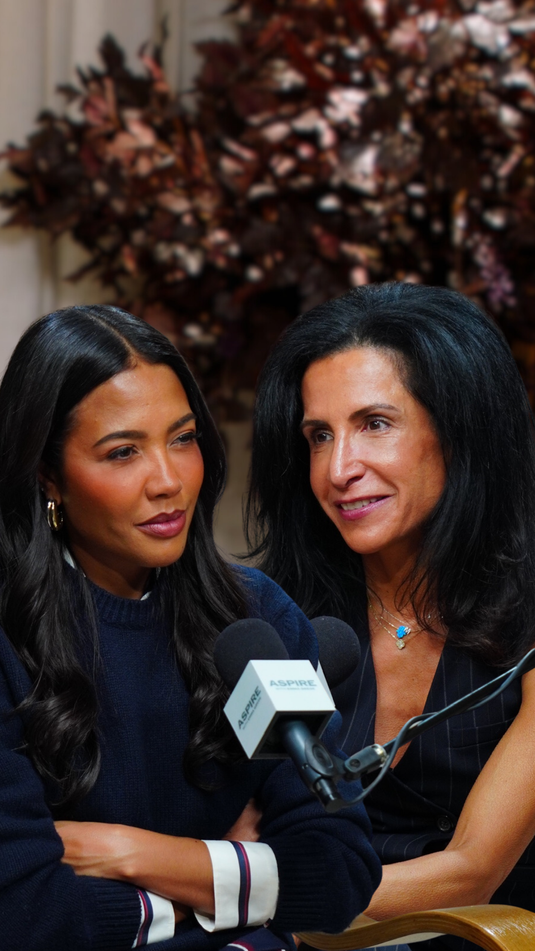 Two women, one in a navy sweater and the other in a pinstriped top, are seated with microphones bearing the ASPIRE logo.