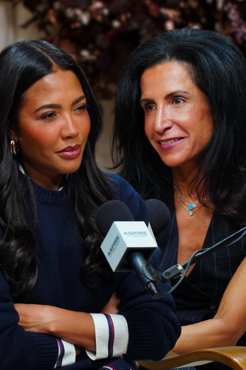 Two women, one in a navy sweater and the other in a pinstriped top, are seated with microphones bearing the ASPIRE logo.