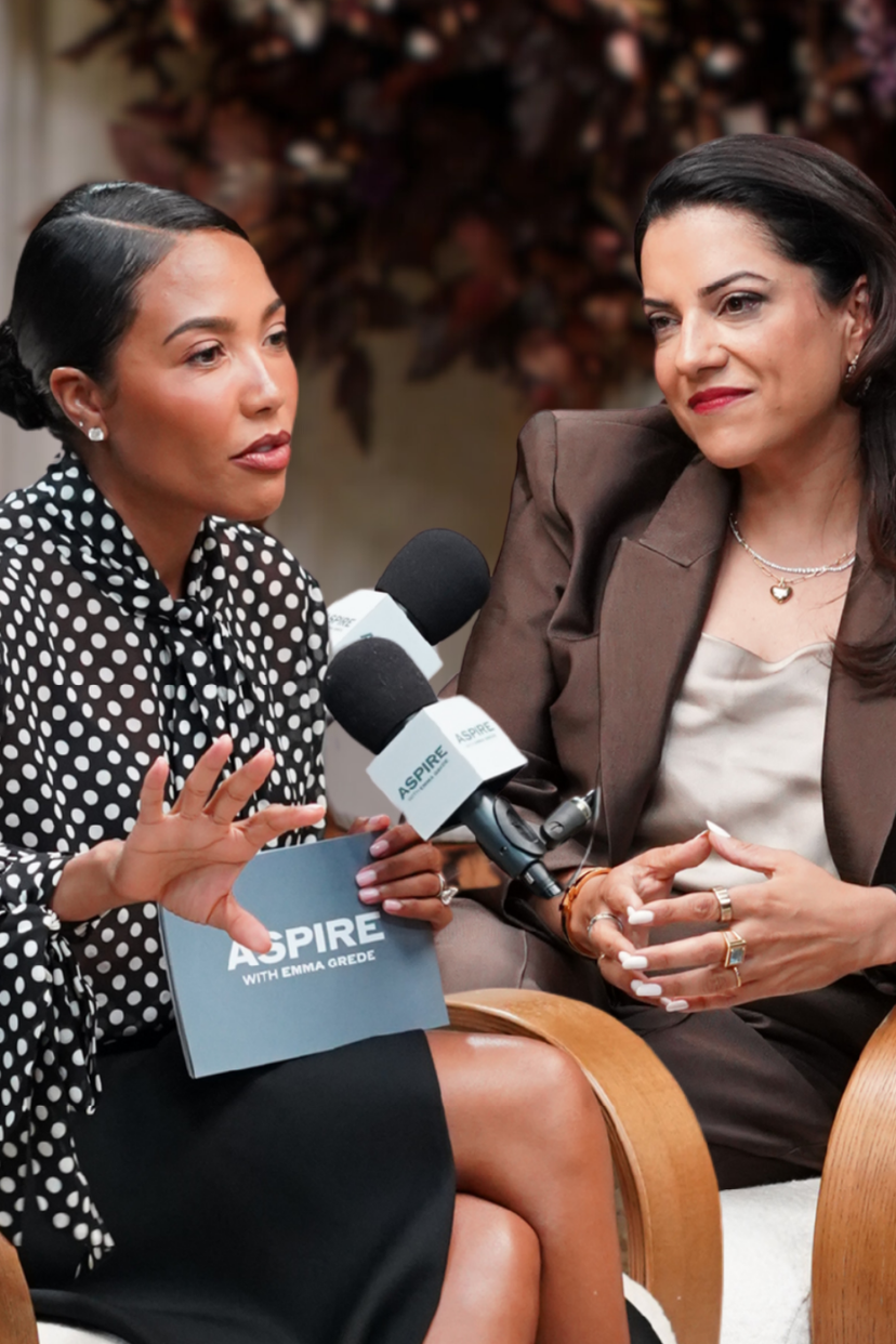 Emma Grede and Reshma Saujani seated for a conversation with microphones, under the title "ARE WE STANDING IN OUR OWN WAY?"