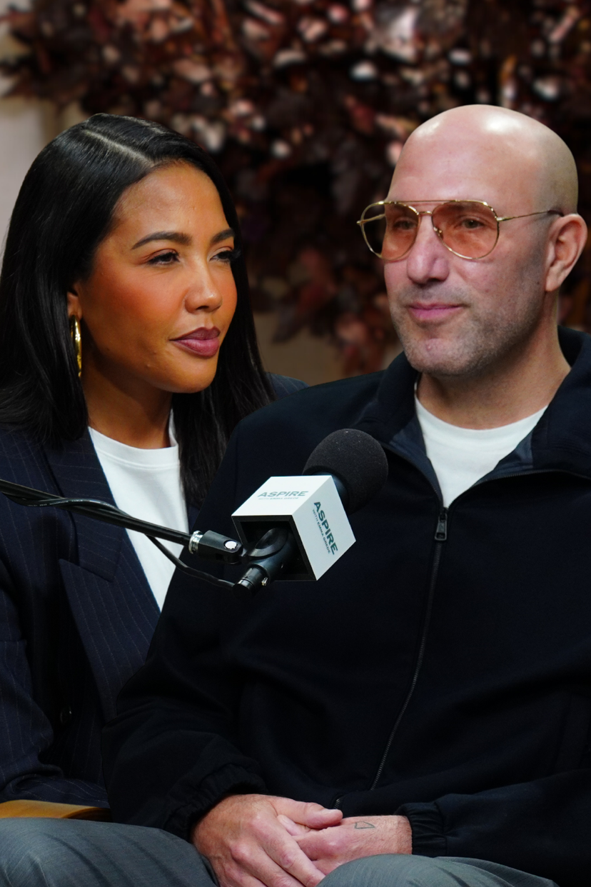 A woman Emma Grede with long dark hair looks towards a bald man Rich Kleiman in tinted glasses, with an ASPIRE microphone between them.