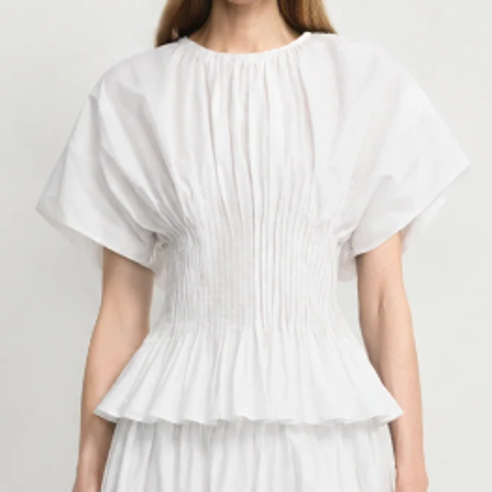 Rue Sophie white peplum blouse featuring short cap sleeves, a gathered round neckline, and an intricately pintucked and smocked waist.