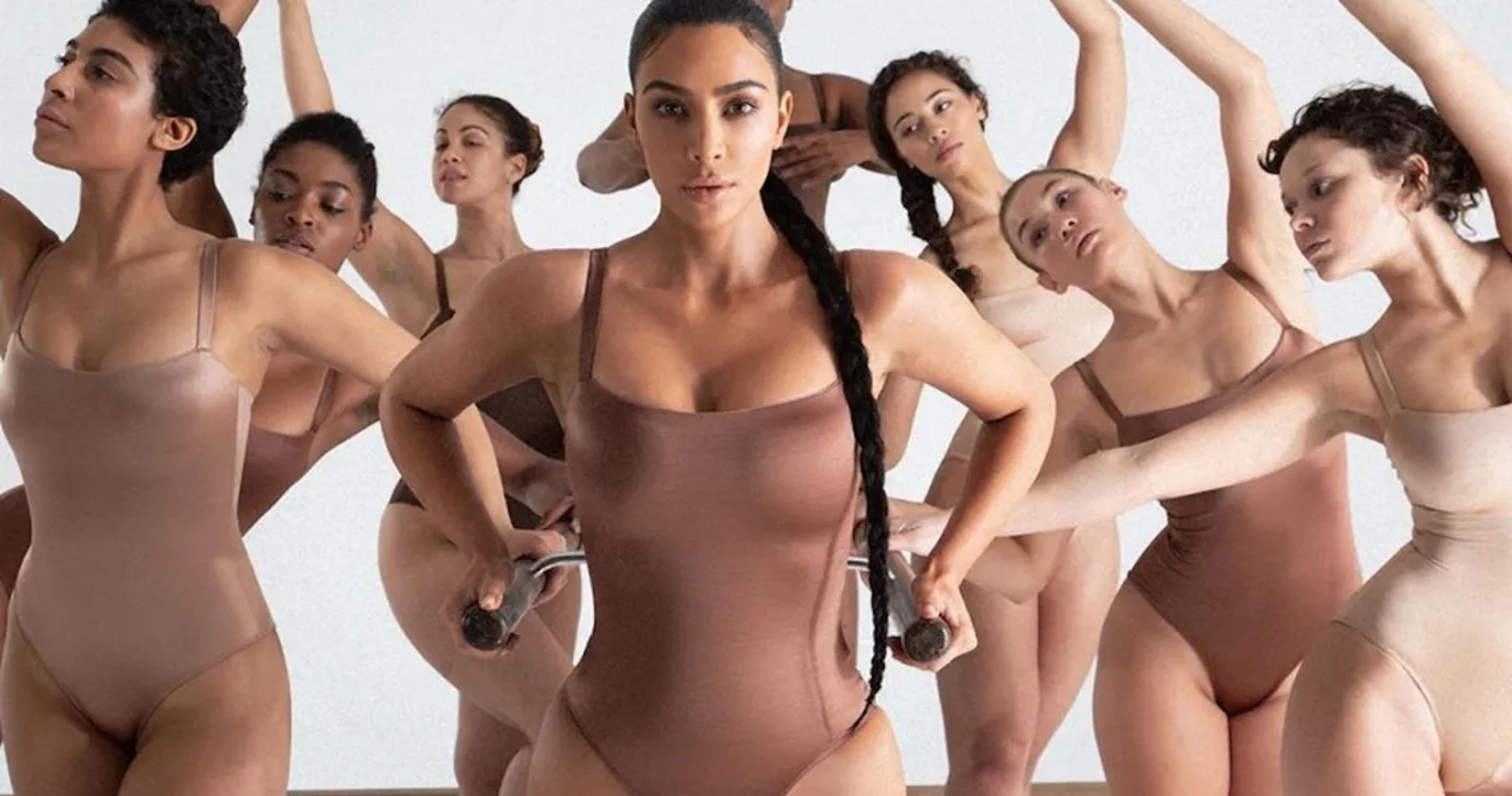 Group of models in neutral-tone bodysuits posing for shapewear brand Skims in a minimalist studio campaign shot