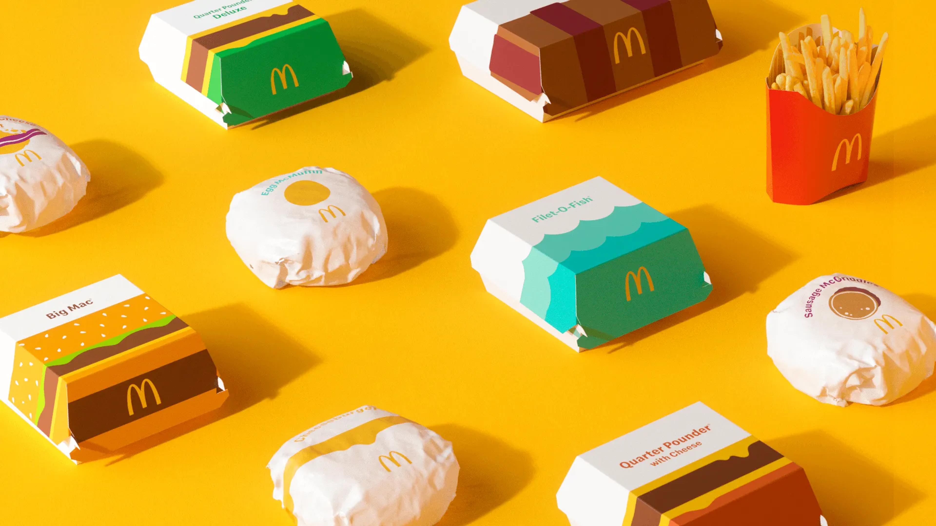 Multiple fast-food items arranged on a solid background, showing repeated use of the same packaging shapes and symbols.