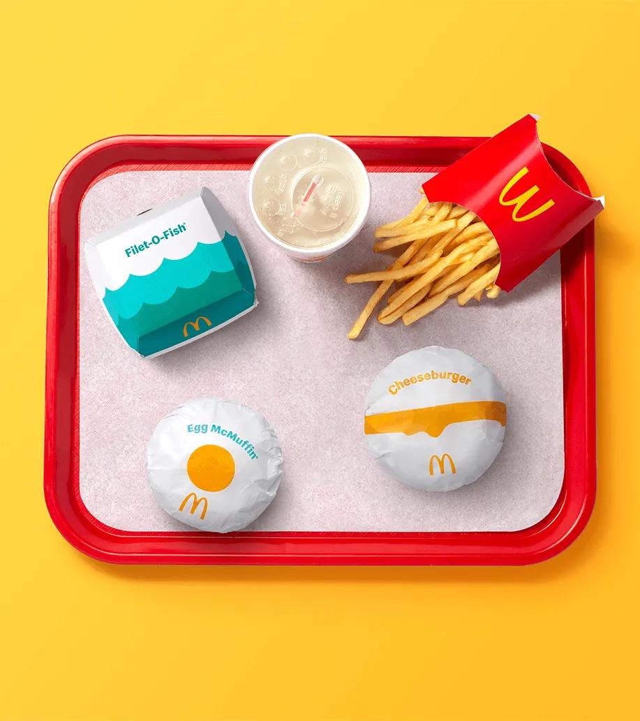 A top-down view of a fast-food meal tray showing uniform packaging design across sandwiches, fries, and drink.