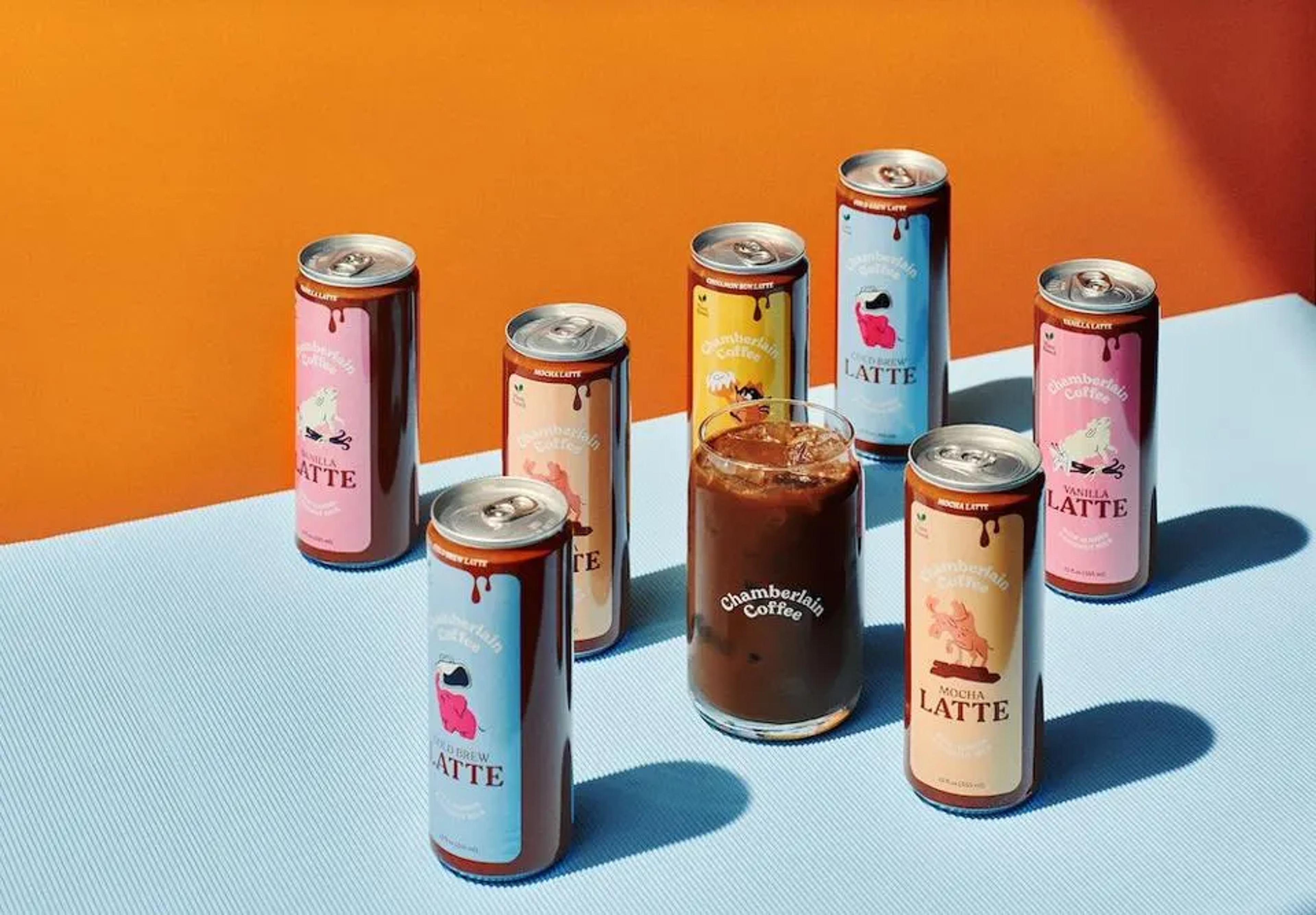 Assorted Chamberlain Coffee canned lattes arranged around an iced glass, highlighting the ready-to-drink product line