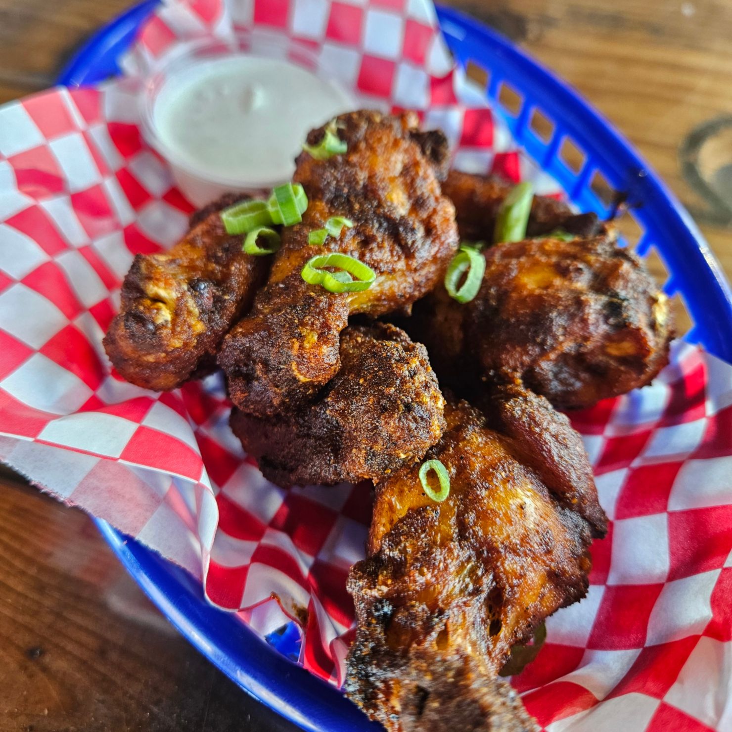 Dry-rub wings in a basket with green onion and ranch
