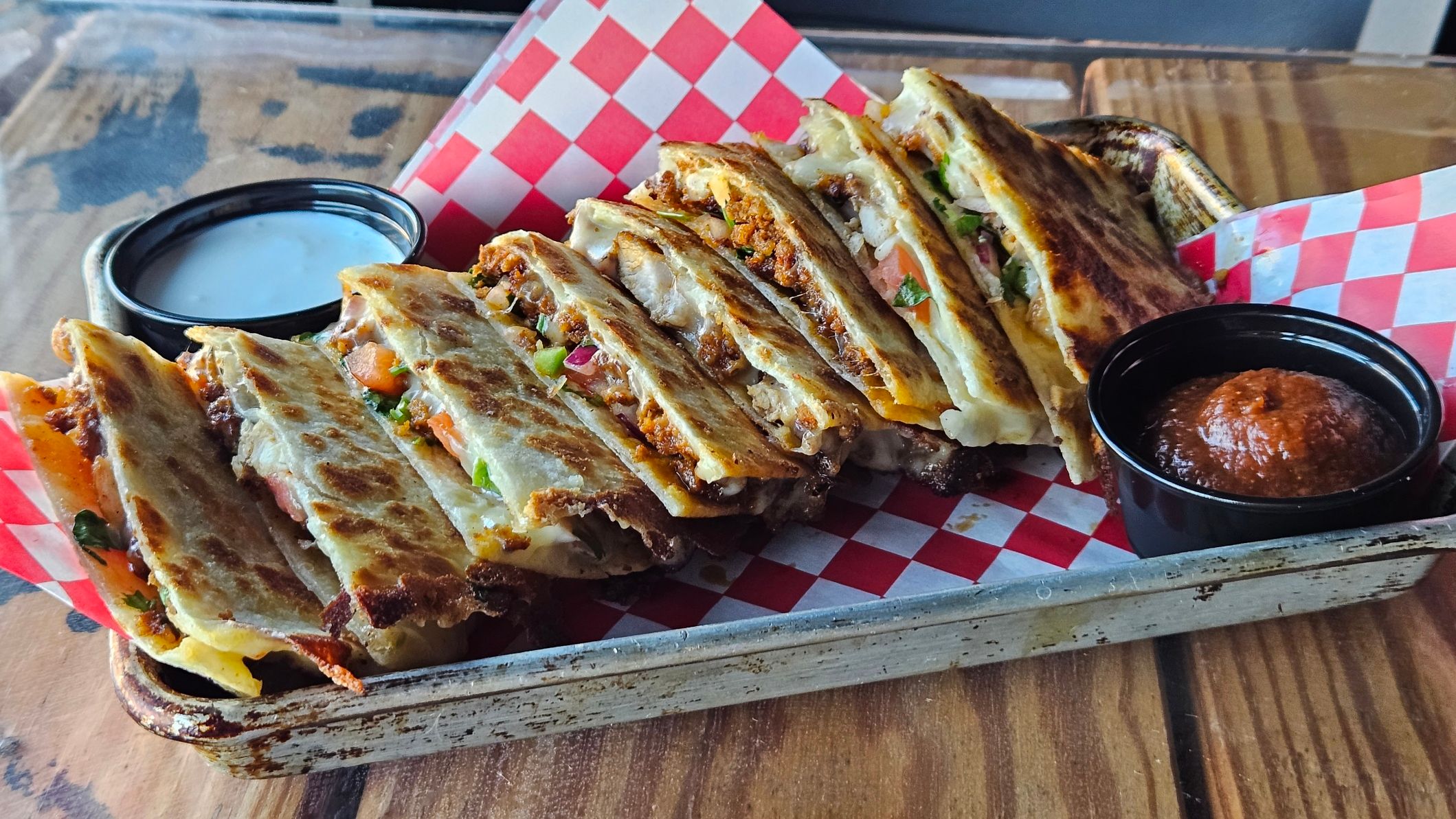 Chorizo quesadilla wedges on checkered paper with ranch and salsa