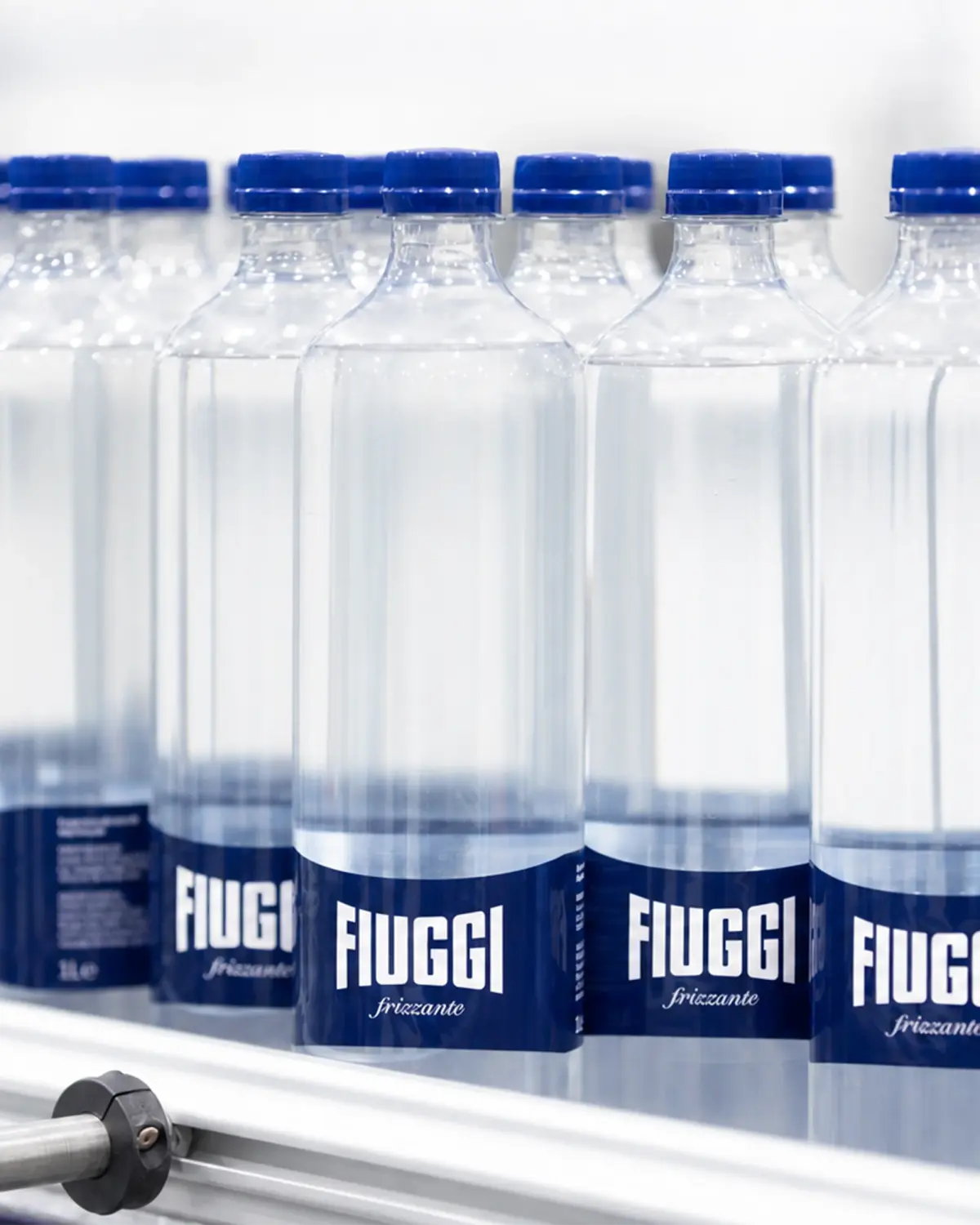 Bottiglie Acqua Fiuggi frizzante con tappo blu sulla linea di produzione