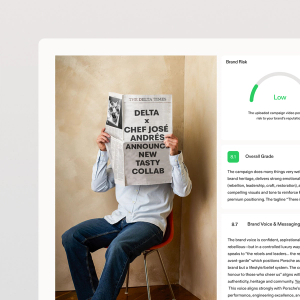 A person sitting on a chair reads a large newspaper with the headline “Delta x Chef José Andrés Announce New Tasty Collab,” while a digital dashboard on the right shows brand risk and overall grade metrics.