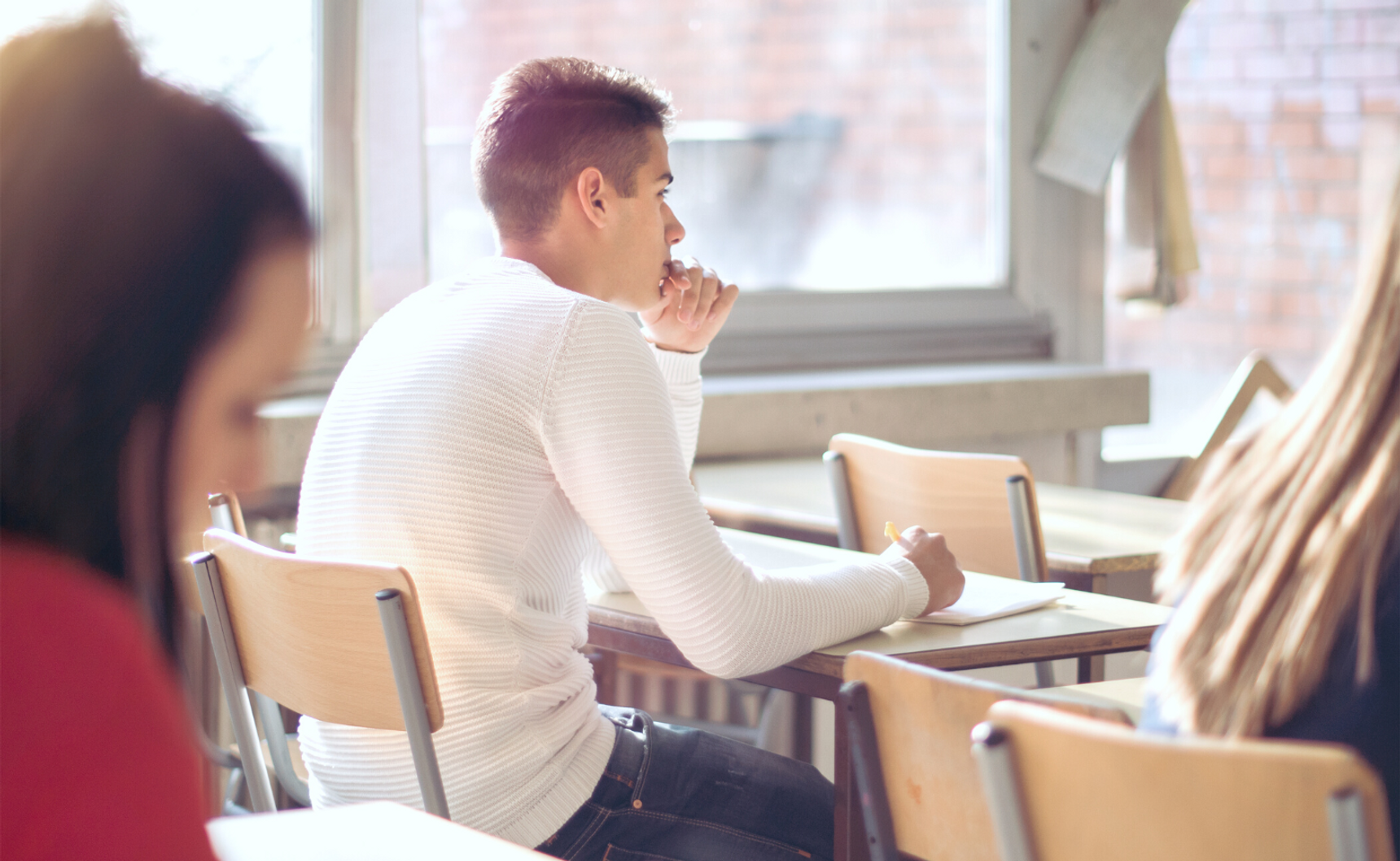 Junge sitzt in einer Klasse verunsichert auf dem Stuhl.