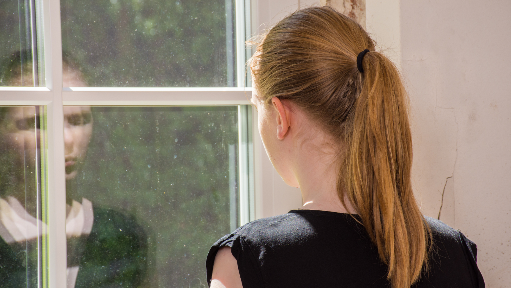 Junge Frau schaut deprimiert aus dem Fenster .