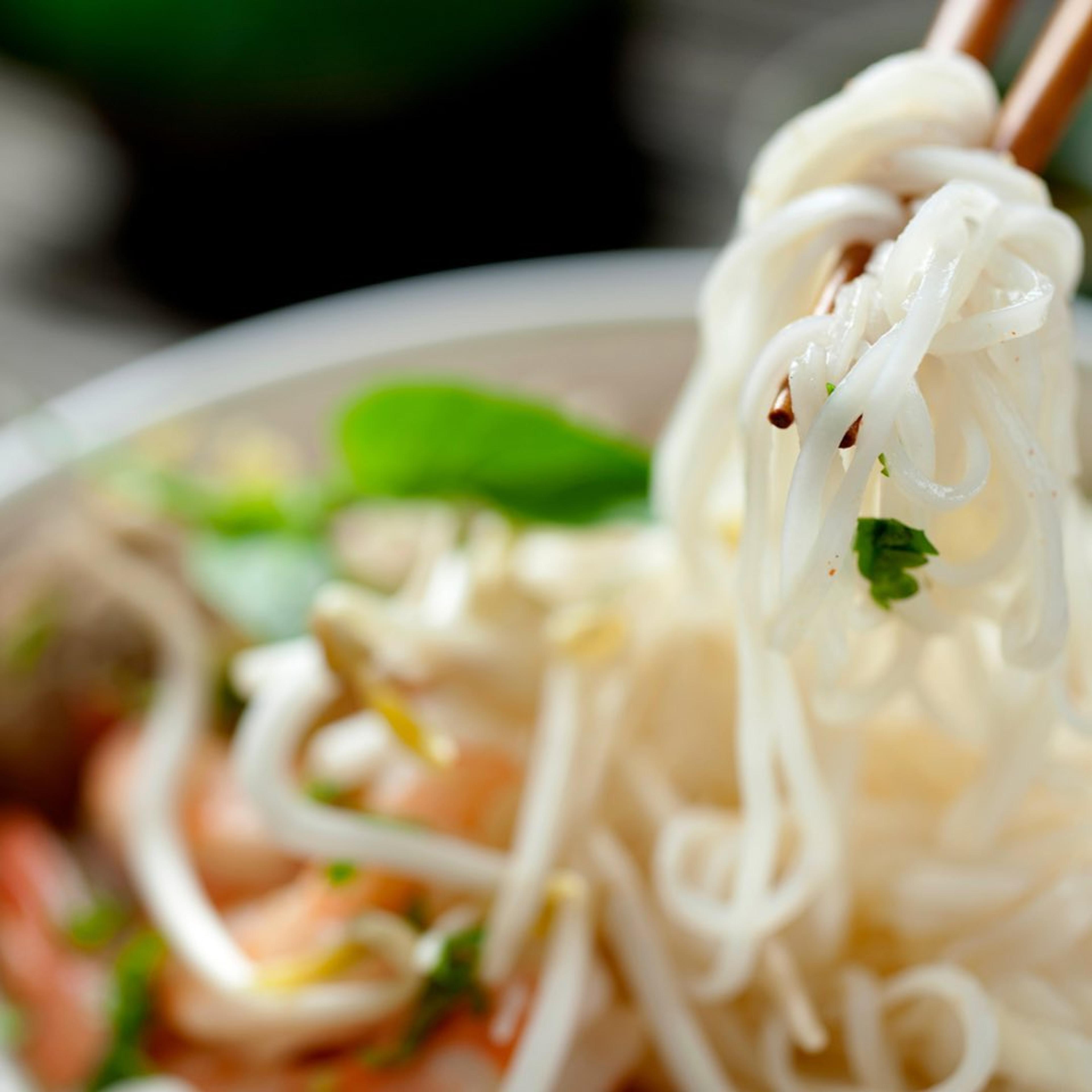 bowl of pho noodles being held up with chopsticks