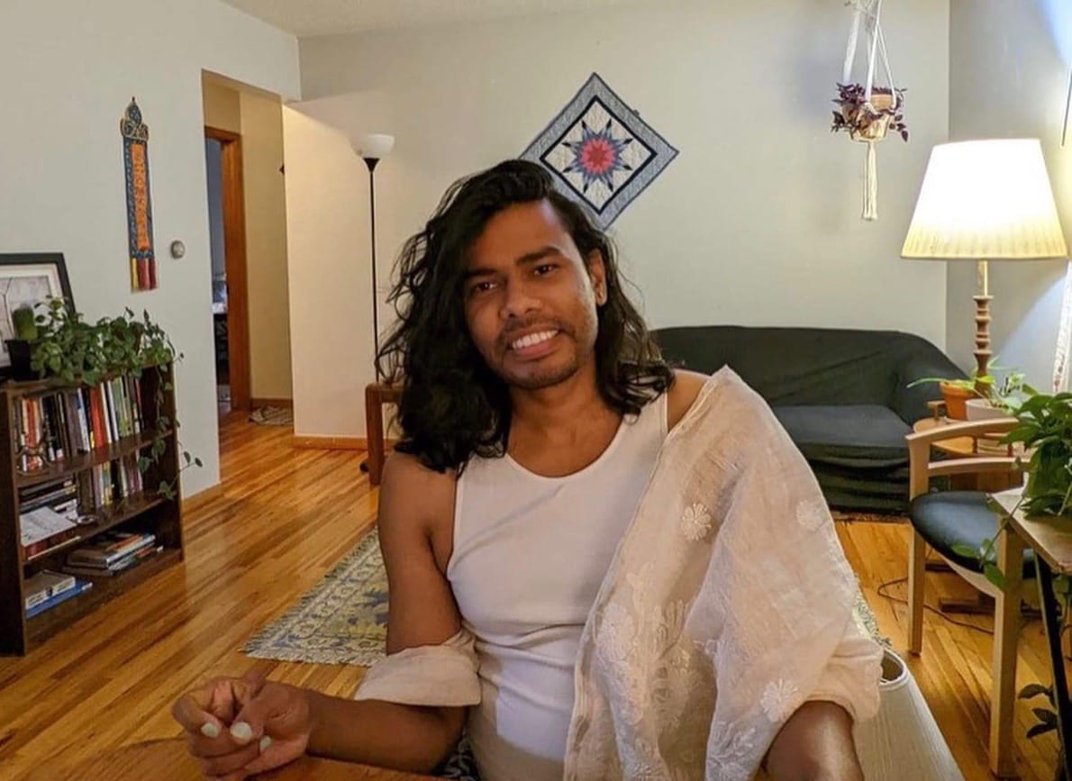 Rajorshi Das seated in a living room, smiling toward the camera.