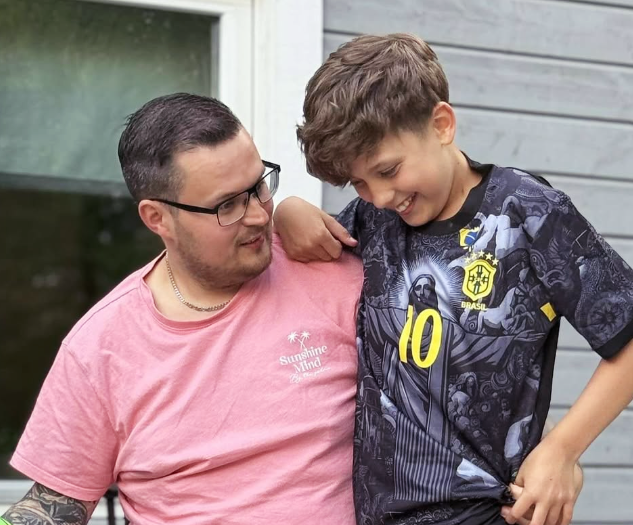 en man i en rosa t-shirt med texten sunshine mind står bredvid en pojke i en svart t-shirt med nummer 10 på