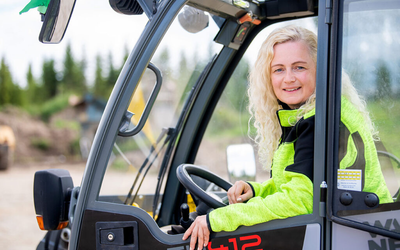 Prosjektleder i byggebransjen sitter i truck og ser smilende i kameraet.