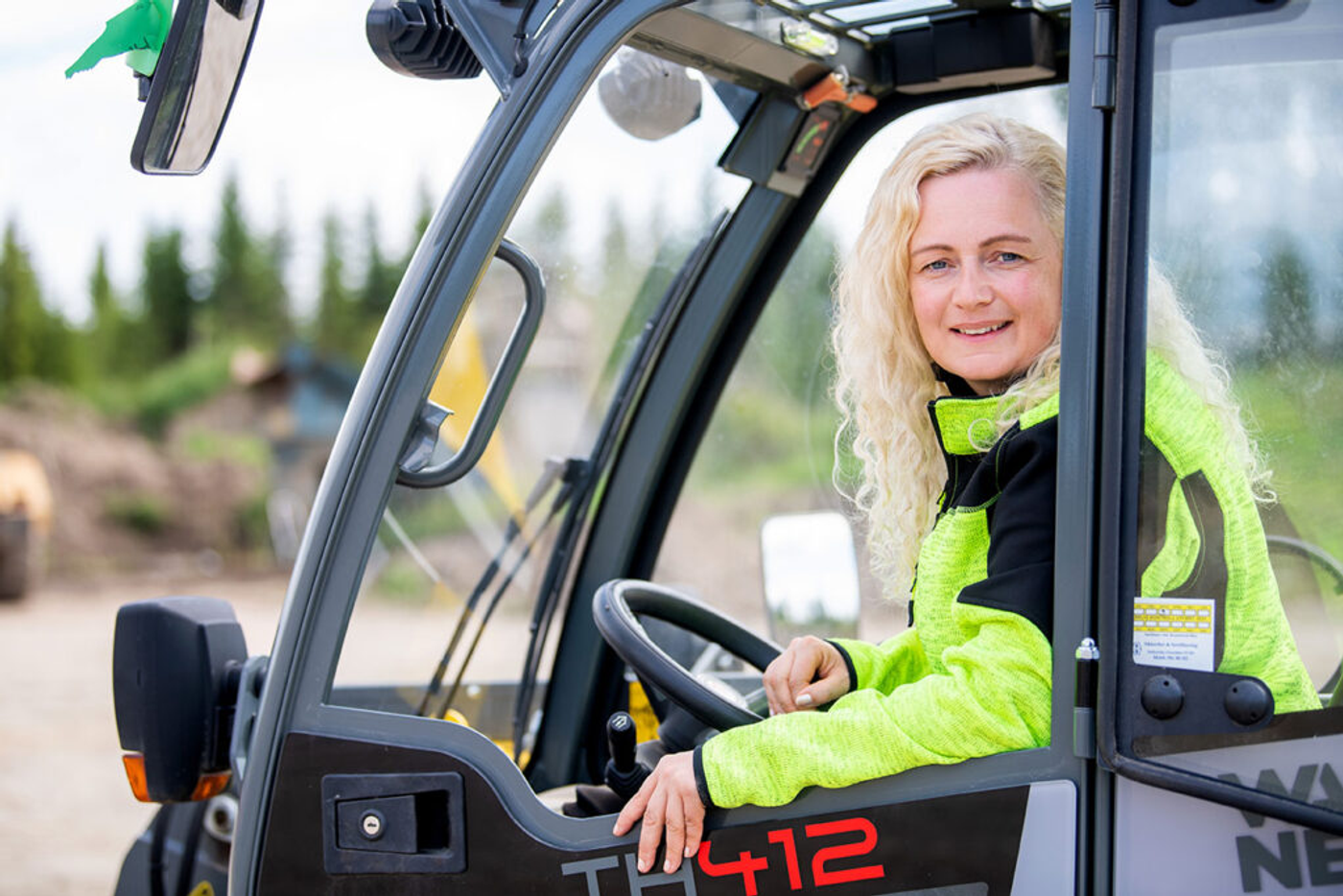 Prosjektleder i byggebransjen sitter i truck og ser smilende i kameraet.