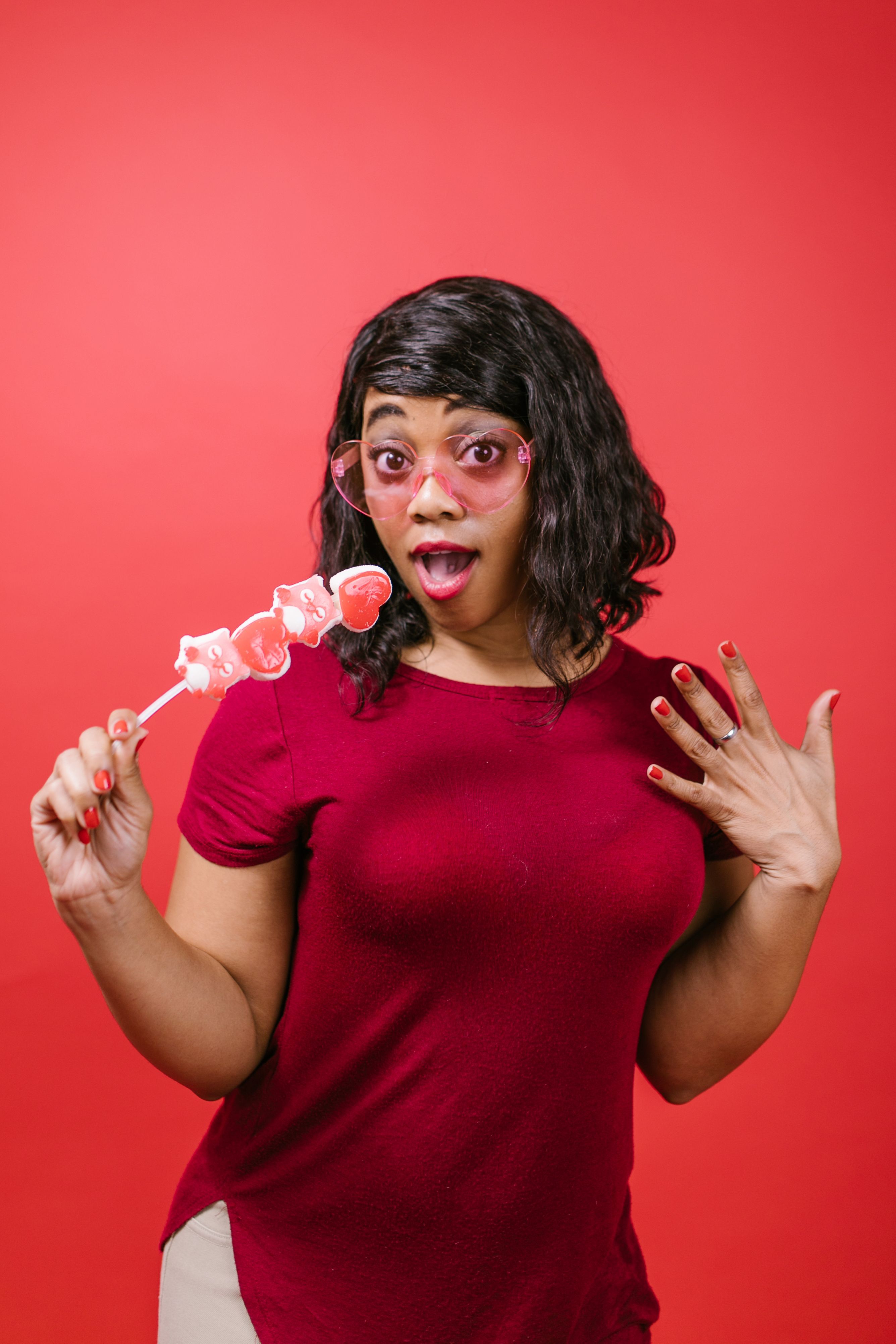 : A surprised woman wearing pink heart-shaped glasses and holding heart candies, symbolizing the realization that relying on casual, 20s-era dating rules no longer works in your 30s.