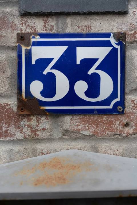 A vintage blue and white sign showing the number 33, symbolizing the transition from high-volume app swiping to seeking genuine compatibility and consistent communication.