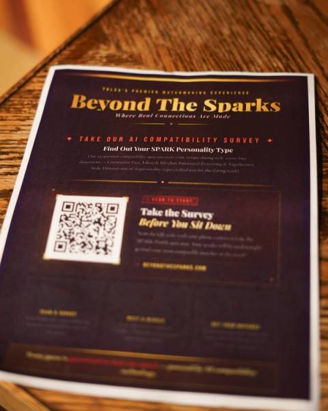 A printed Beyond The Sparks table card on a wood table with a QR code to take the SPARK compatibility survey.
