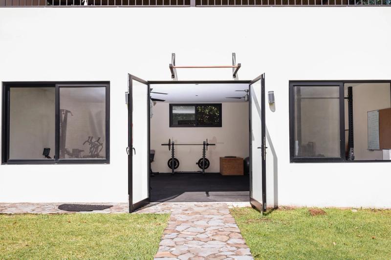 The gym at Atenas, a white building with its double doors open onto a stone path and lawn.