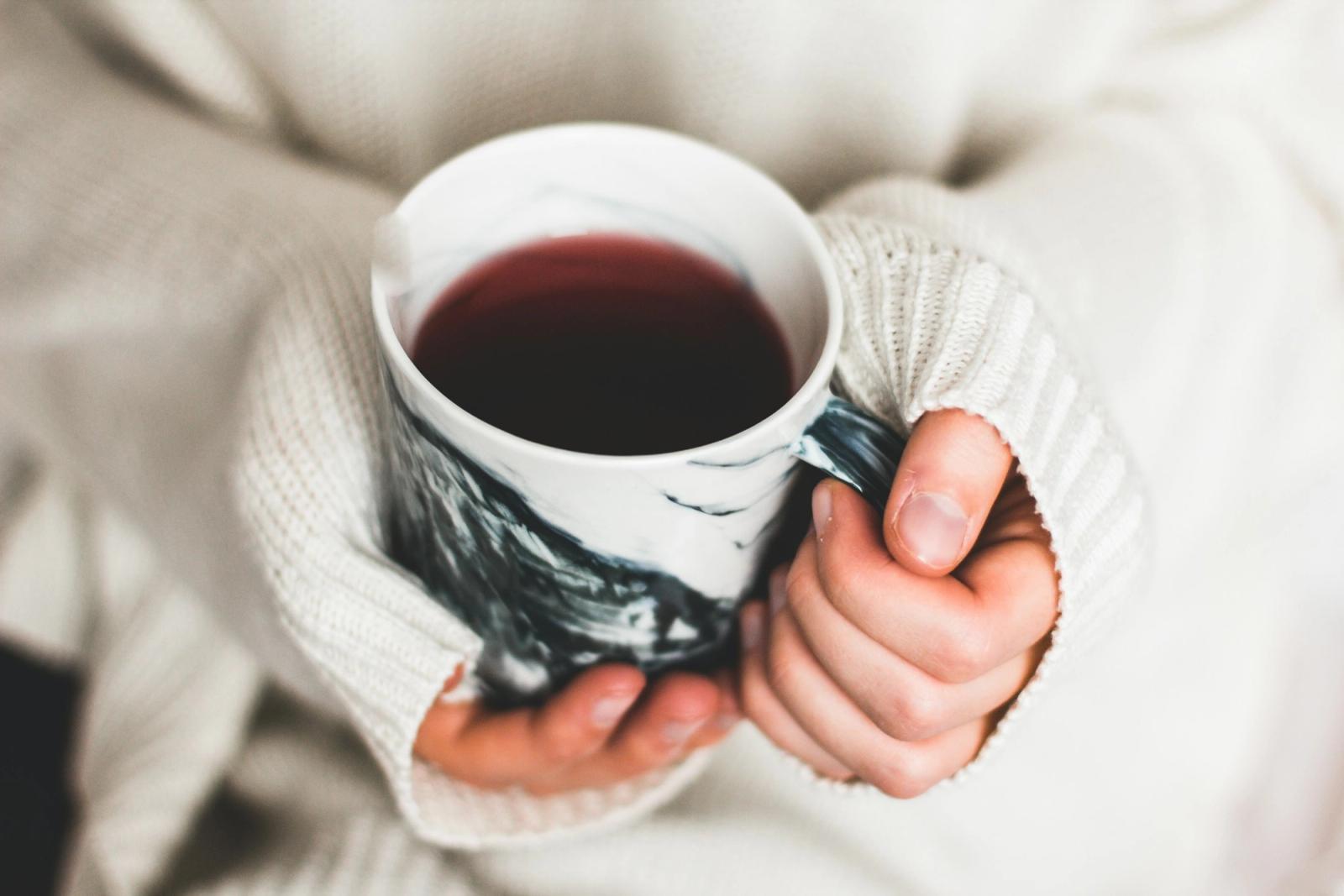 Hands in a soft sweater cradling a warm mug.
