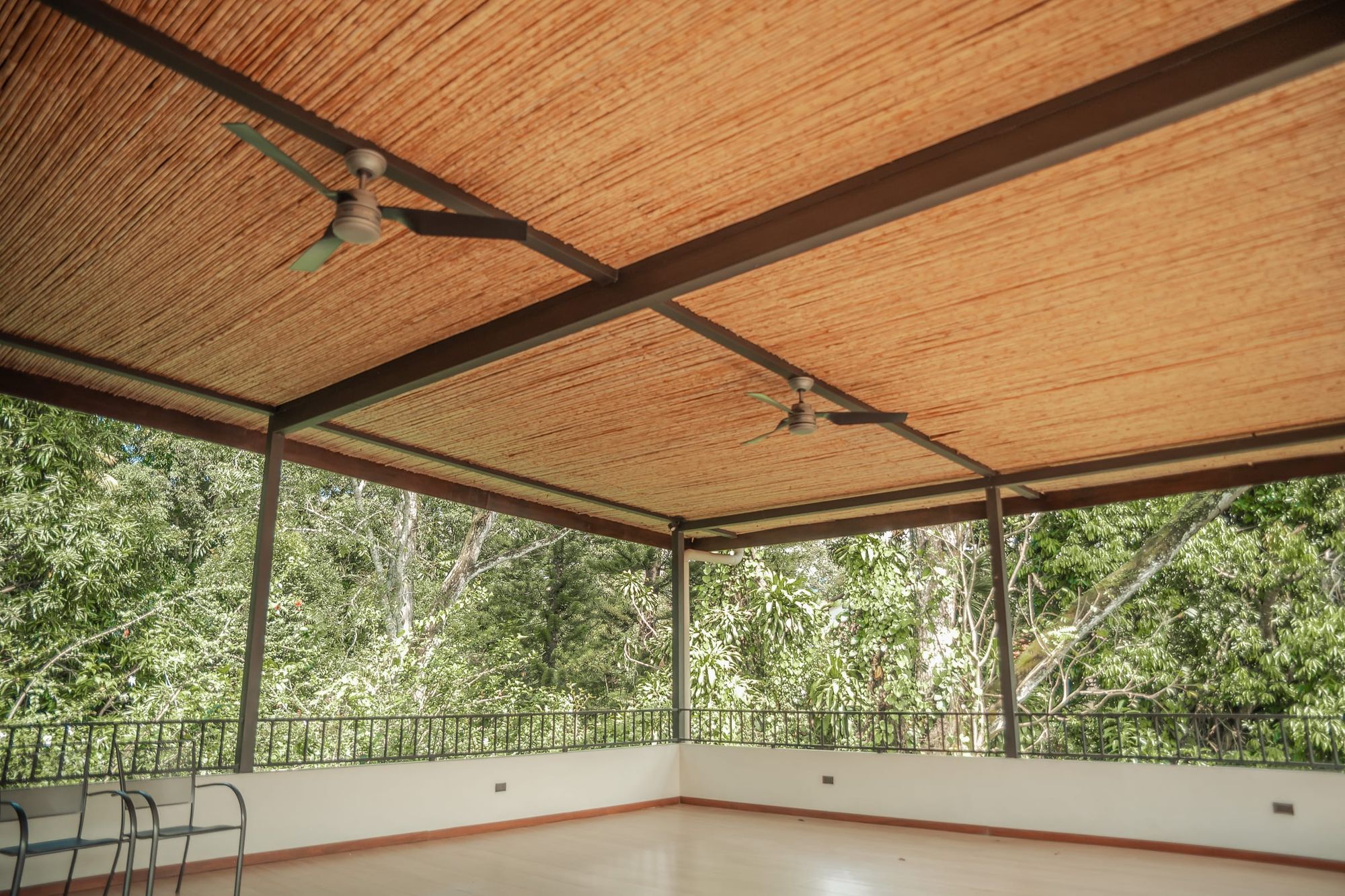 The open-air yoga hall at Atenas: a wide wooden floor under a bamboo ceiling, open on all sides to the forest.