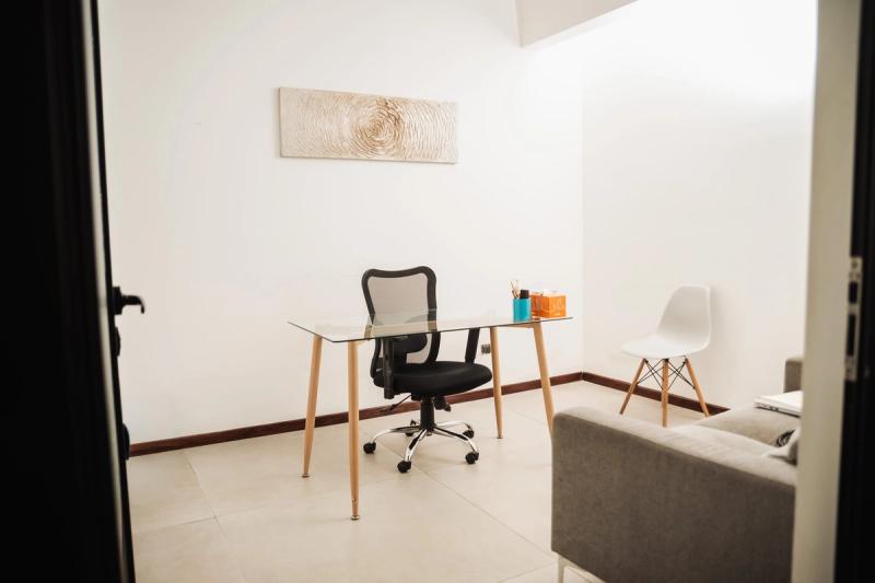 A simple therapy office at San José with a desk, two chairs and a sofa.