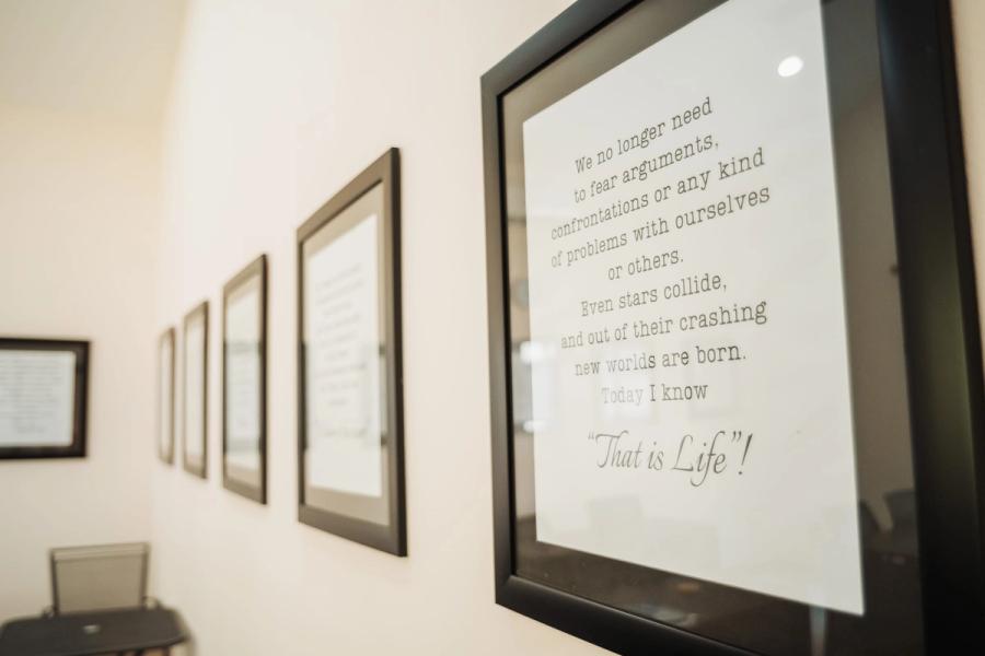 A framed quotation on a white wall, ending with the words "That is Life", one of a row of framed texts.