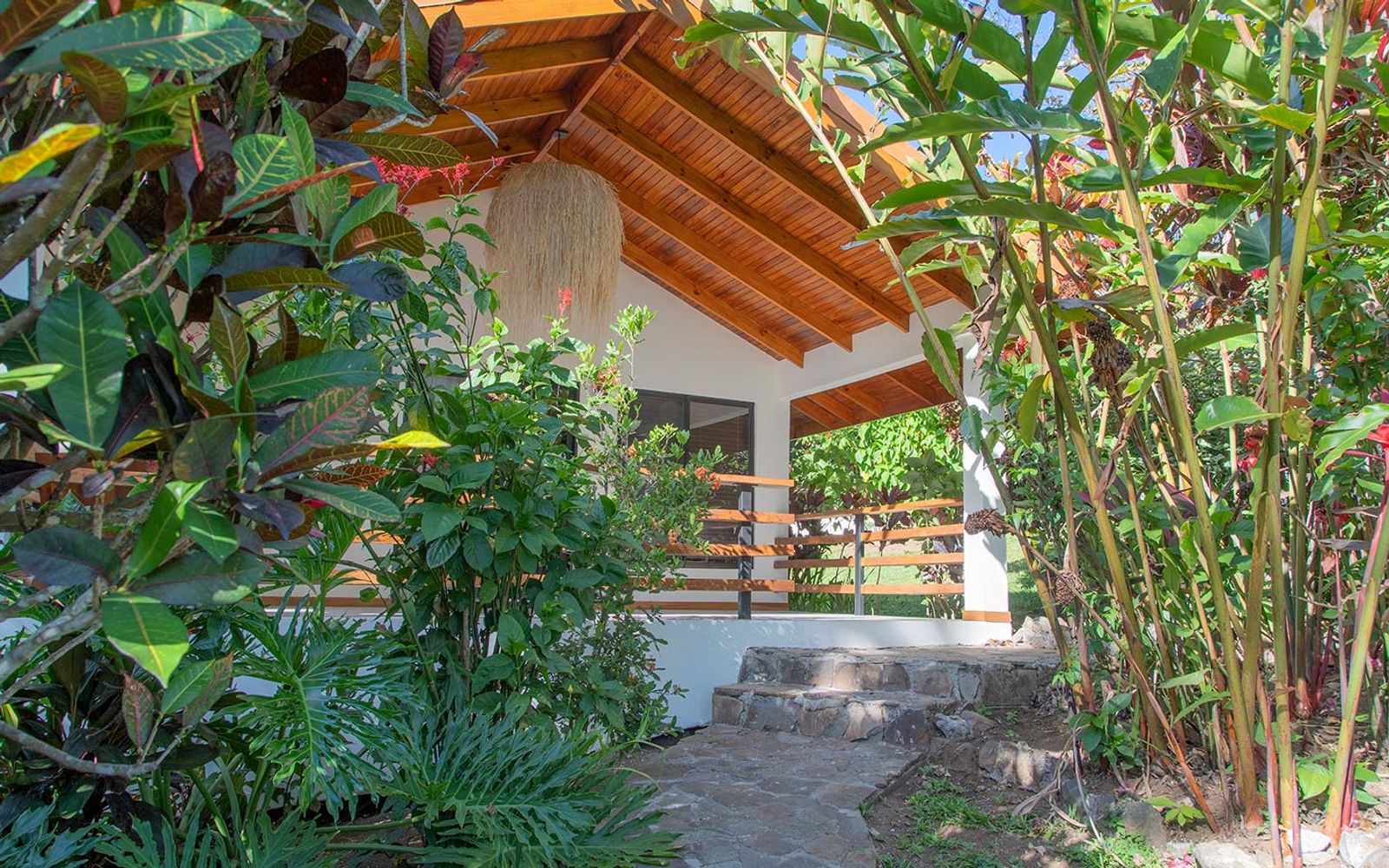 The covered terrace entrance of a private casita at Riverside, framed by tropical foliage.