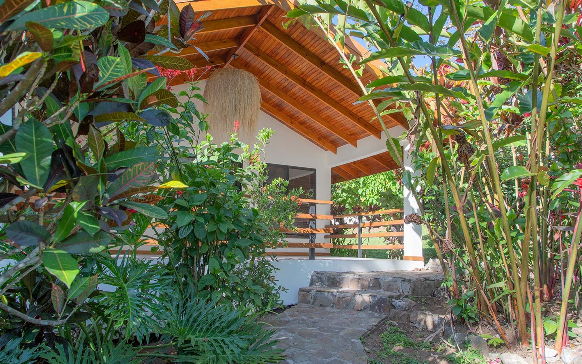 The covered terrace entrance of a private casita at Riverside, framed by tropical foliage.